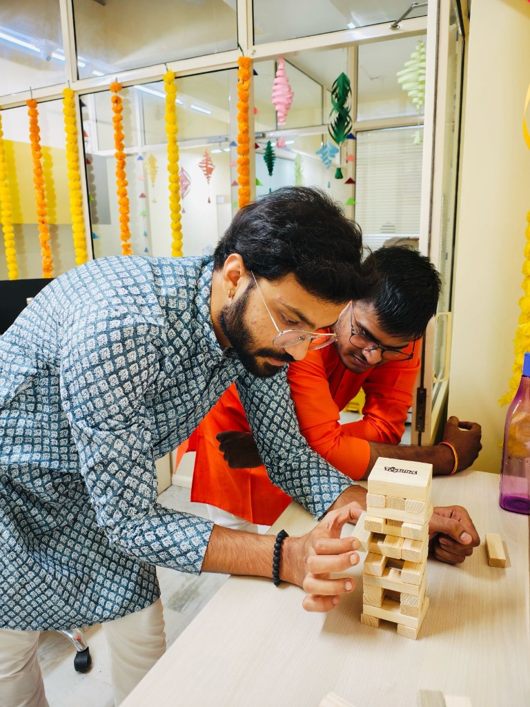 Team members playing a wooden block game during a festive office activity