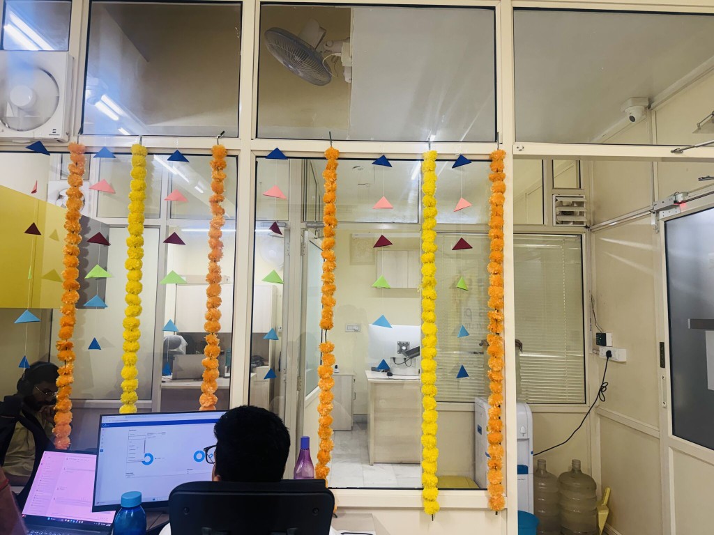 Festive office workspace with marigold garlands and team members at their desks